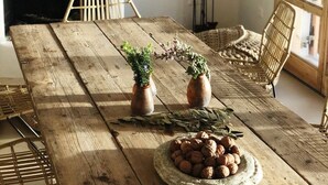 A rustic wooden dining table with two potted plants and a bowl of nuts. - Kea Retreat (Kea)