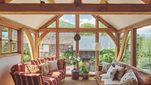 Um quarto acolhedor com dois sofás, um tapete e vista para uma casa por grandes janelas.