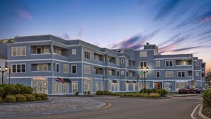 A multi-story hotel with a modern design, featuring a prominent entrance with a flag, and a well-maintained landscaped area in front.