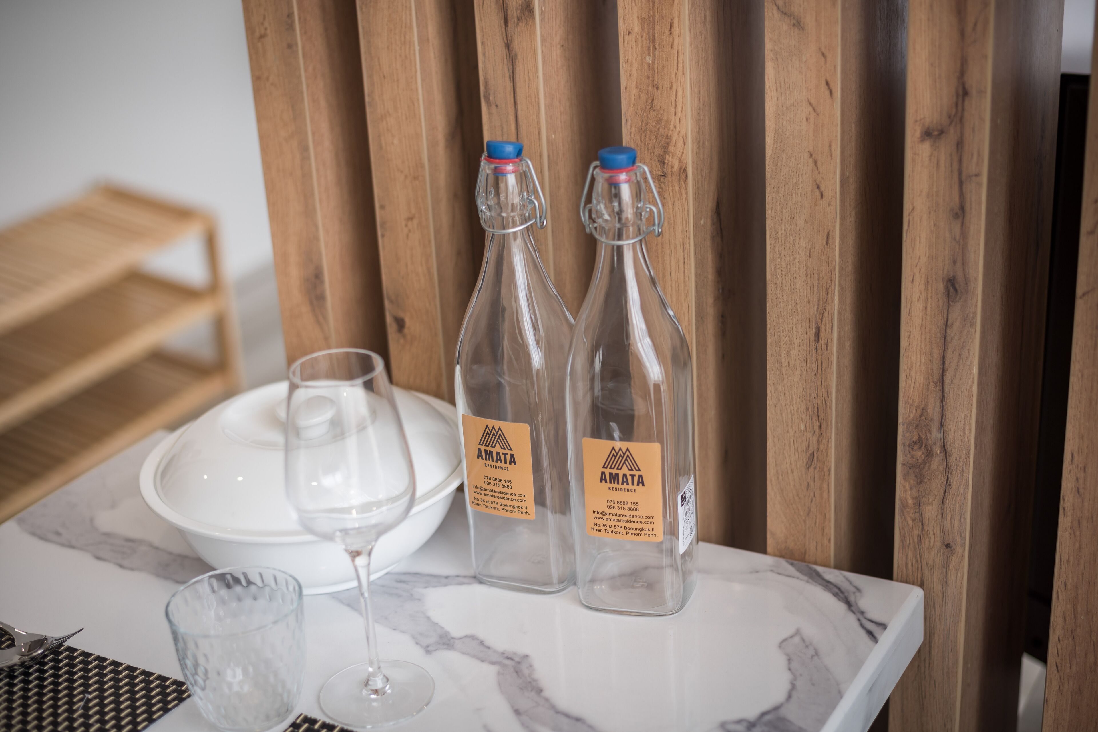 A marble table with two glass bottles, a wine glass, and a white plate.