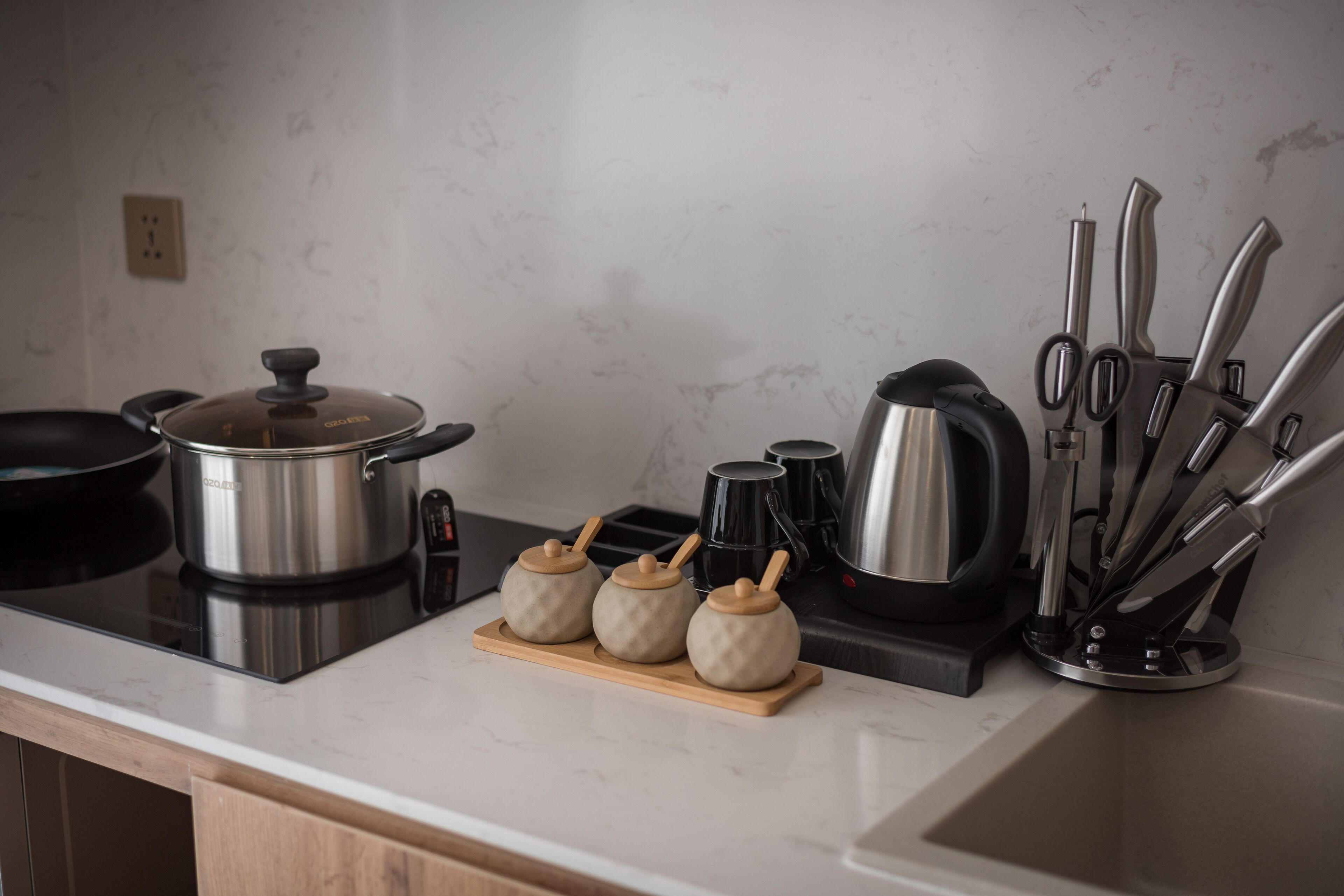 A kitchen with a stove, pots, a coffee maker, and a knife set.