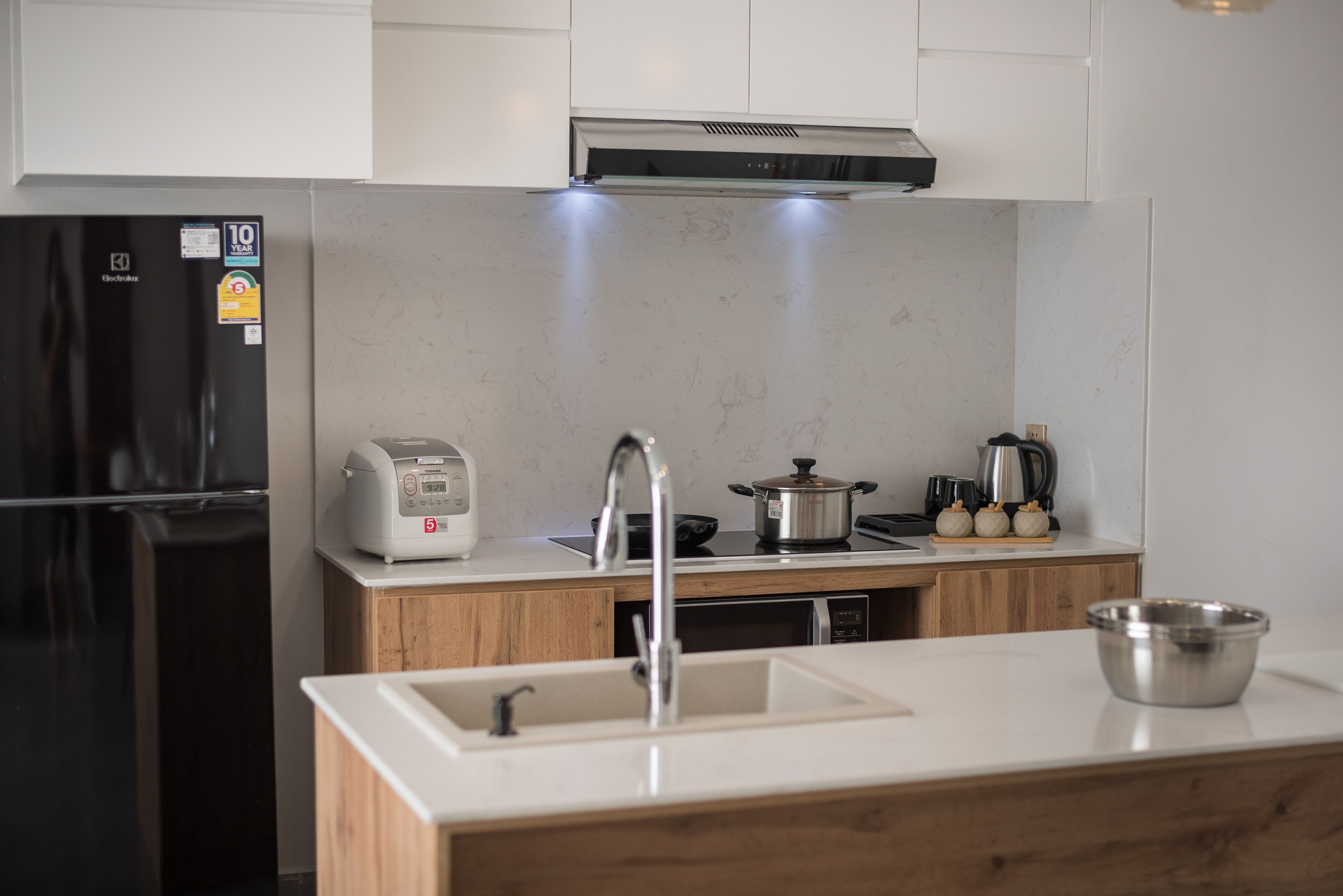 A modern kitchen with a black refrigerator, a toaster, a sink, and a stove.