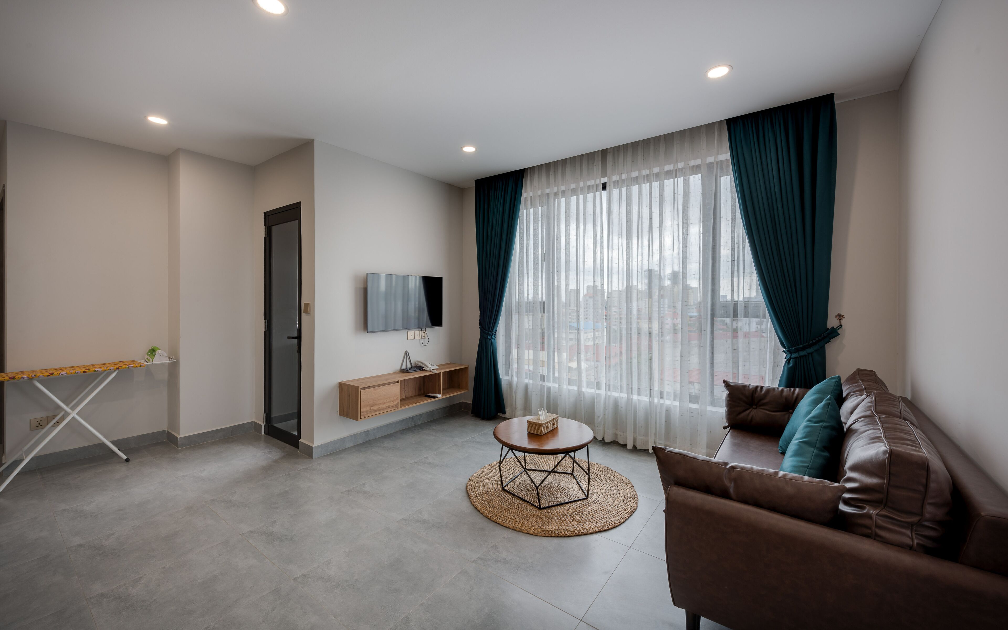 A modern living room with a sofa, a coffee table, a TV, and a window with curtains.