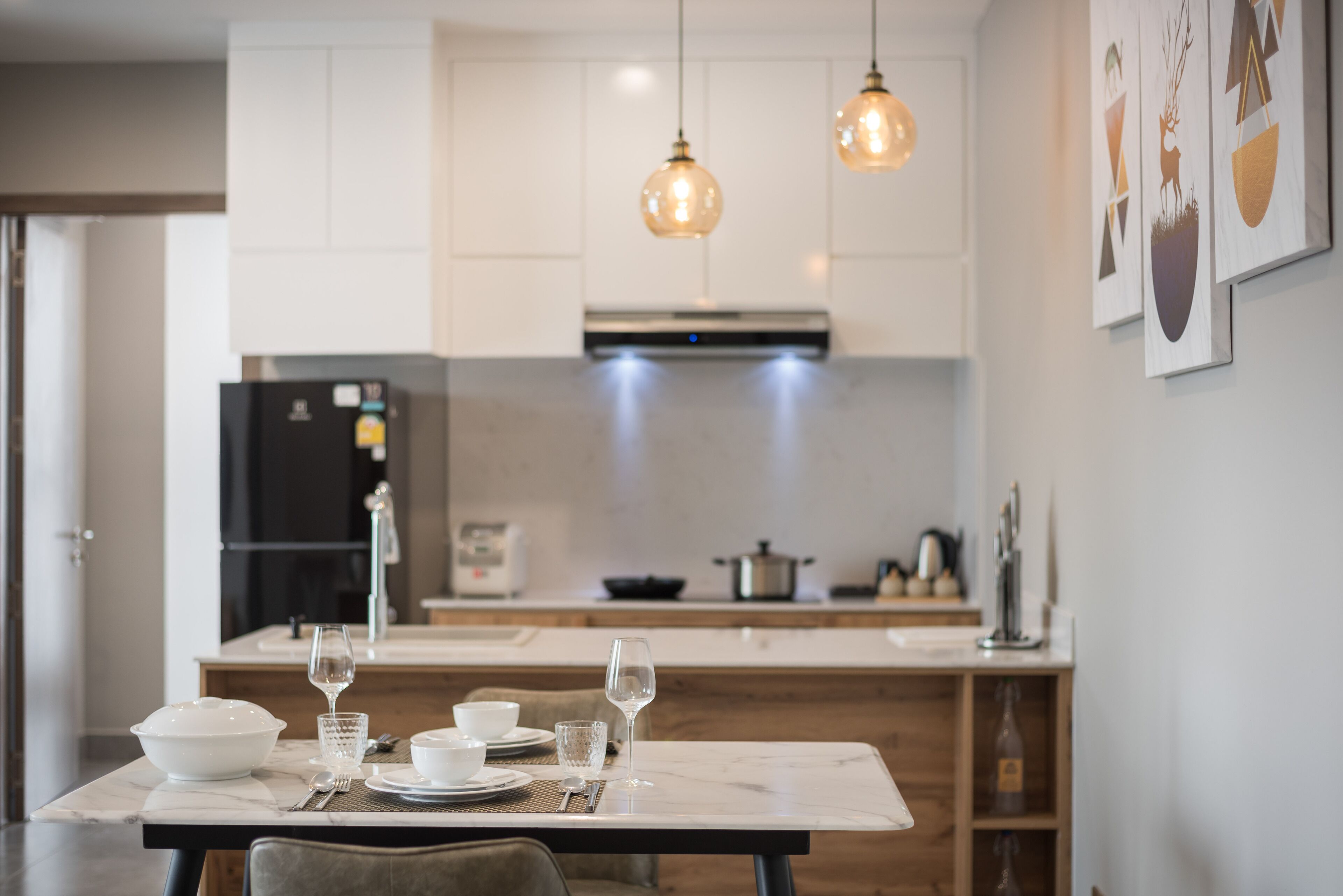 A modern kitchen with white cabinets, a marble countertop, and pendant lighting.