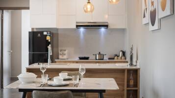 A modern kitchen with white cabinets, a marble countertop, and pendant lighting.