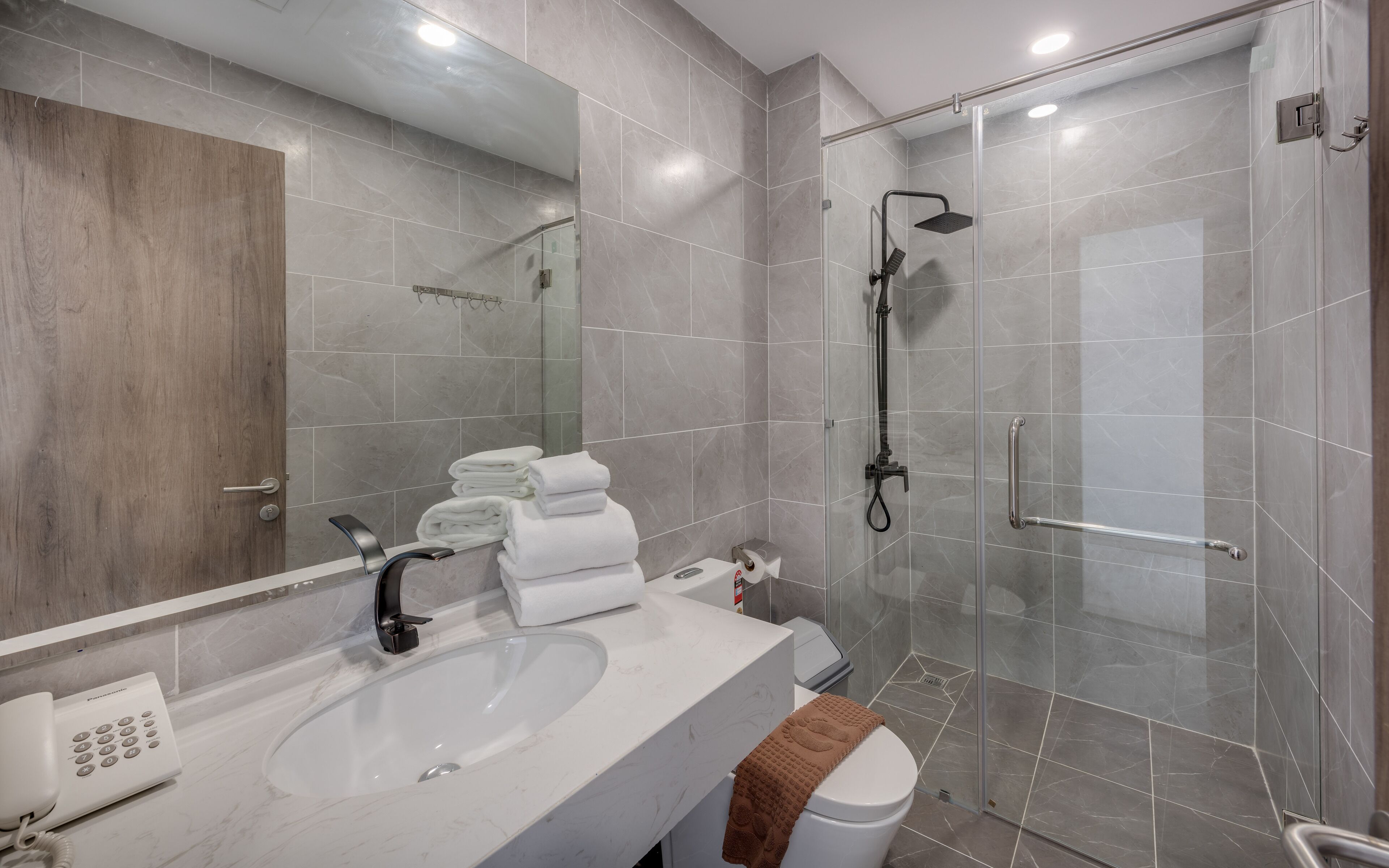 Un baño moderno con ducha de vidrio, lavamanos blanco y un inodoro.