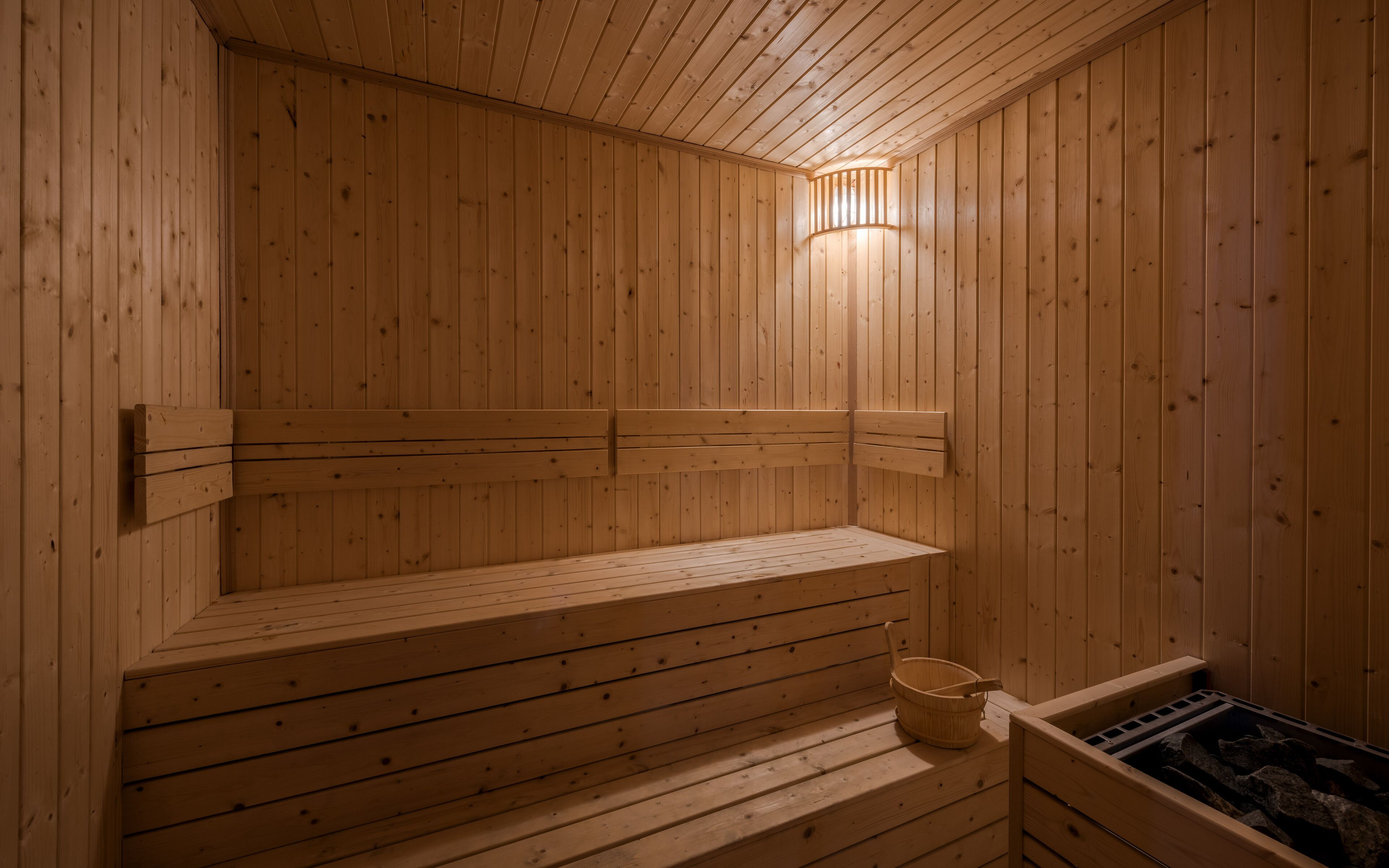 Una sauna de madera con bancos y un cubo.