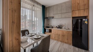 Una cocina moderna con armarios de madera, un refrigerador negro y un comedor con una mesa dispuesta para dos.