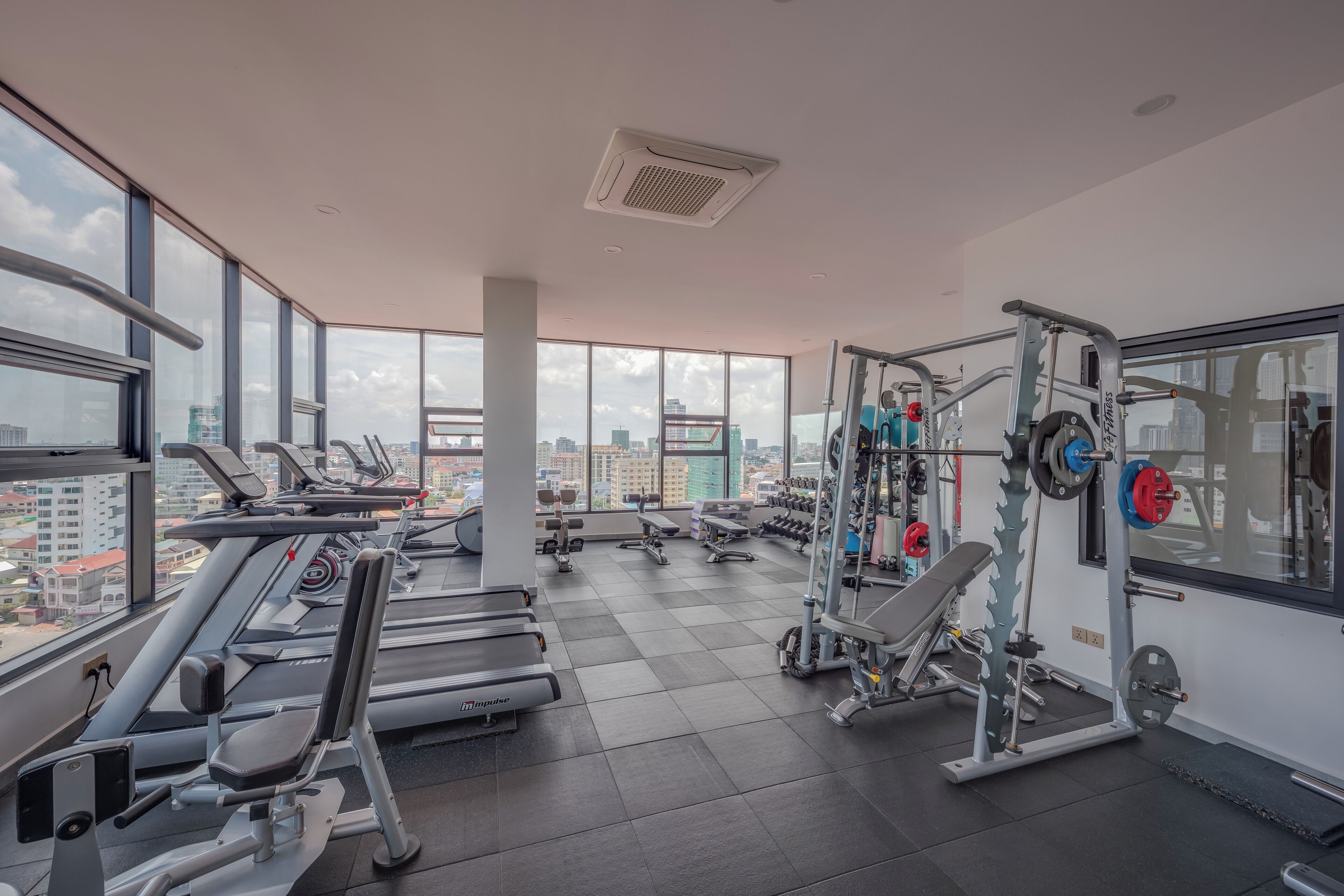 A gym with treadmills, weight machines, and a view of the city.