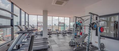 A gym with treadmills, weight machines, and a view of the city.