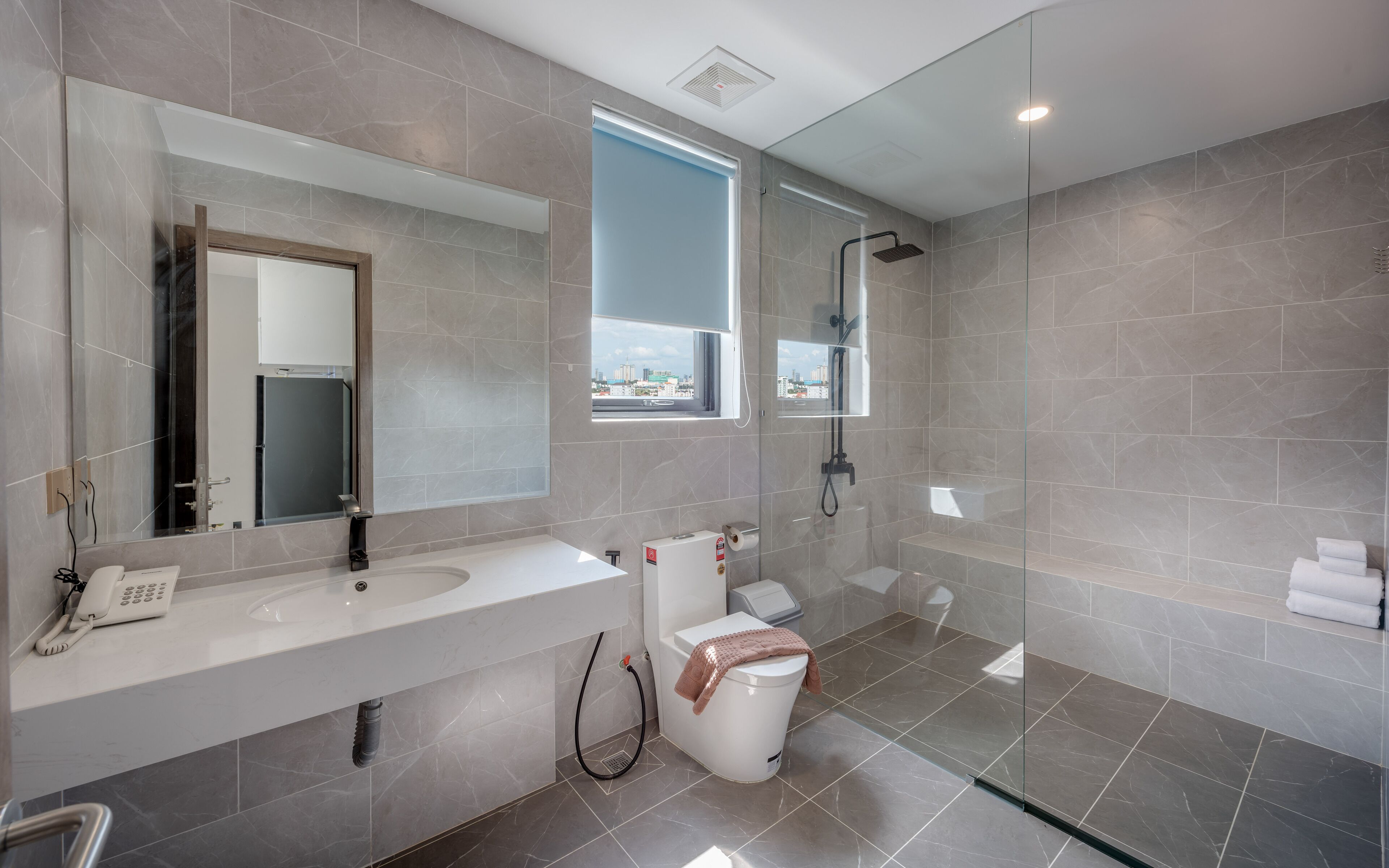 A modern bathroom with a large mirror, a sink, a toilet, and a shower.