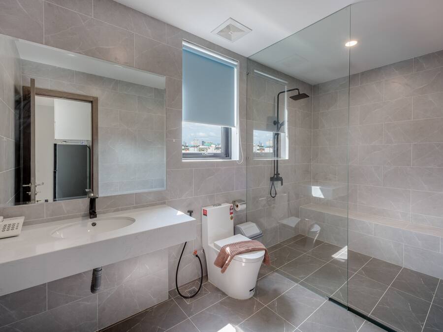 Un baño moderno con un espejo grande, un lavabo, un inodoro y una ducha.