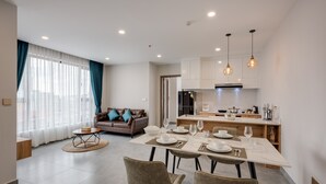 Una sala de estar moderna con un sofá, una mesa de comedor para cuatro personas y una cocina al fondo.