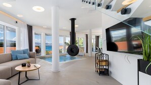 Un interior moderno con un gran ventanal, un sofá, una mesa de centro, una silla colgante y una chimenea.