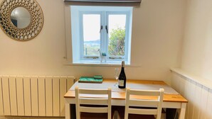 Uma área de refeições com mesa e cadeiras, janela com vista, radiador e um espelho decorativo.
