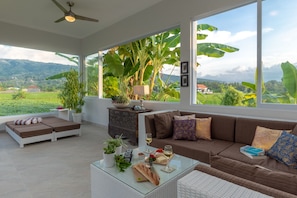 Relax in a stylish room with a panoramic view of lush greenery and a comfortable seating area.
