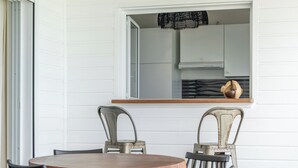 A dining area with a round wooden table and four chairs, a window with a view of the kitchen, and a ceiling with exposed beams. - Only 4 View Rooftop Centre Sainte Anne (sainte anne)