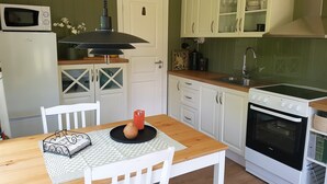 A compact kitchen with white cabinets, a microwave, a stove, and a sink.