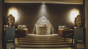 Un vestíbulo con chimenea de piedra, dos estatuas de Buda y suelo a cuadros.