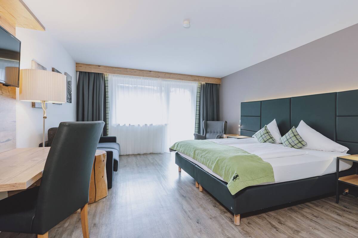 Quarto de hotel moderno com uma cama grande, uma escrivaninha e uma cadeira.