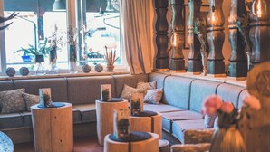 Un rincón acogedor con sofá y mesas redondas de madera, decorado con plantas y pequeñas esculturas.