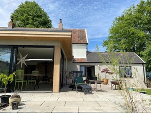 Enjoy the patio's seating options and potted plants, surrounded by a brick chimney and a tiled roof.