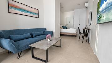 A modern, well-lit room with a blue sofa, a small table, and a TV displaying a scenic view.