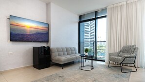 Ein modernes Wohnzimmer mit einer Couch, einem Sessel, einem Couchtisch und einem an der Wand befestigten Fernseher.