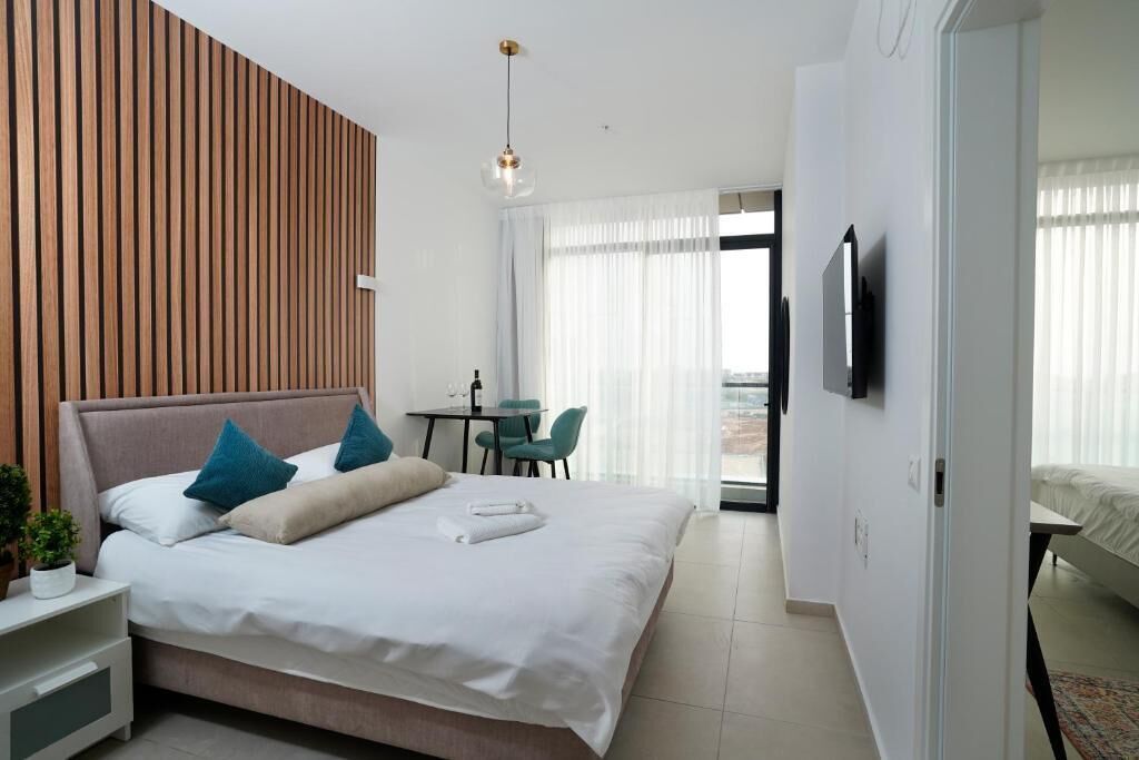 Una habitación de hotel moderna con una cama grande, un escritorio y un balcón con vistas.