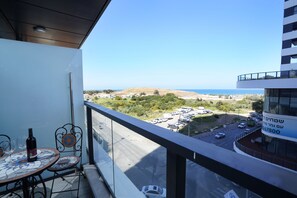A balcony with a view of a parking lot and a hilly landscape. - Hi - Yam SeaView Apartments & Suites (Bat Yam)