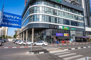 A modern building with multiple commercial spaces, including a hotel and various shops. - Hi - Yam SeaView Apartments & Suites (Bat Yam)