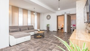 Un salon moderne avec un canapé d’angle, une table basse ronde et un comptoir d’accueil en bois.