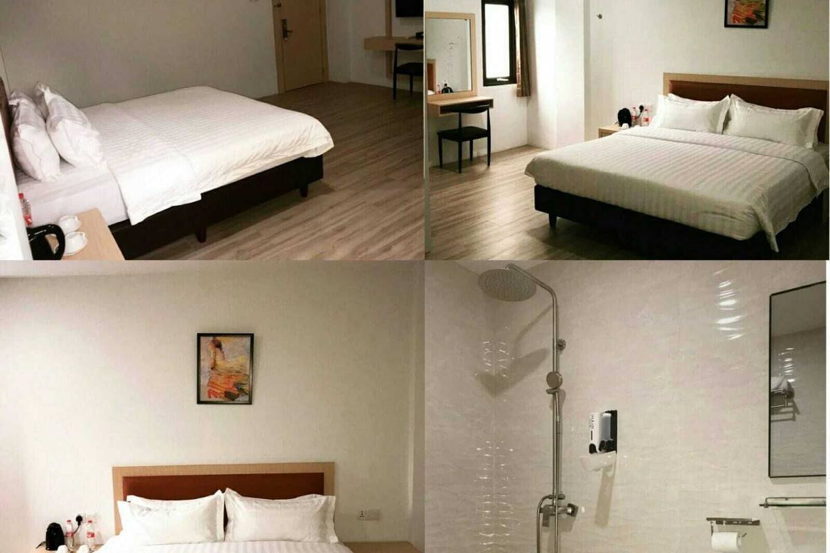 A hotel room with a bed, a desk, a chair, a shower, and a bathroom with a sink and toilet.
