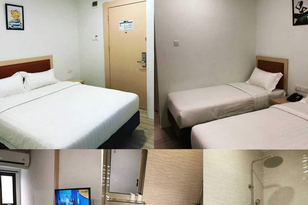 A hotel room with a large bed, a smaller bed, a TV, a bathroom with a sink, toilet, and shower.