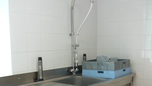Una cocina de acero inoxidable con lavavajillas integrado, un lavamanos y un grifo.