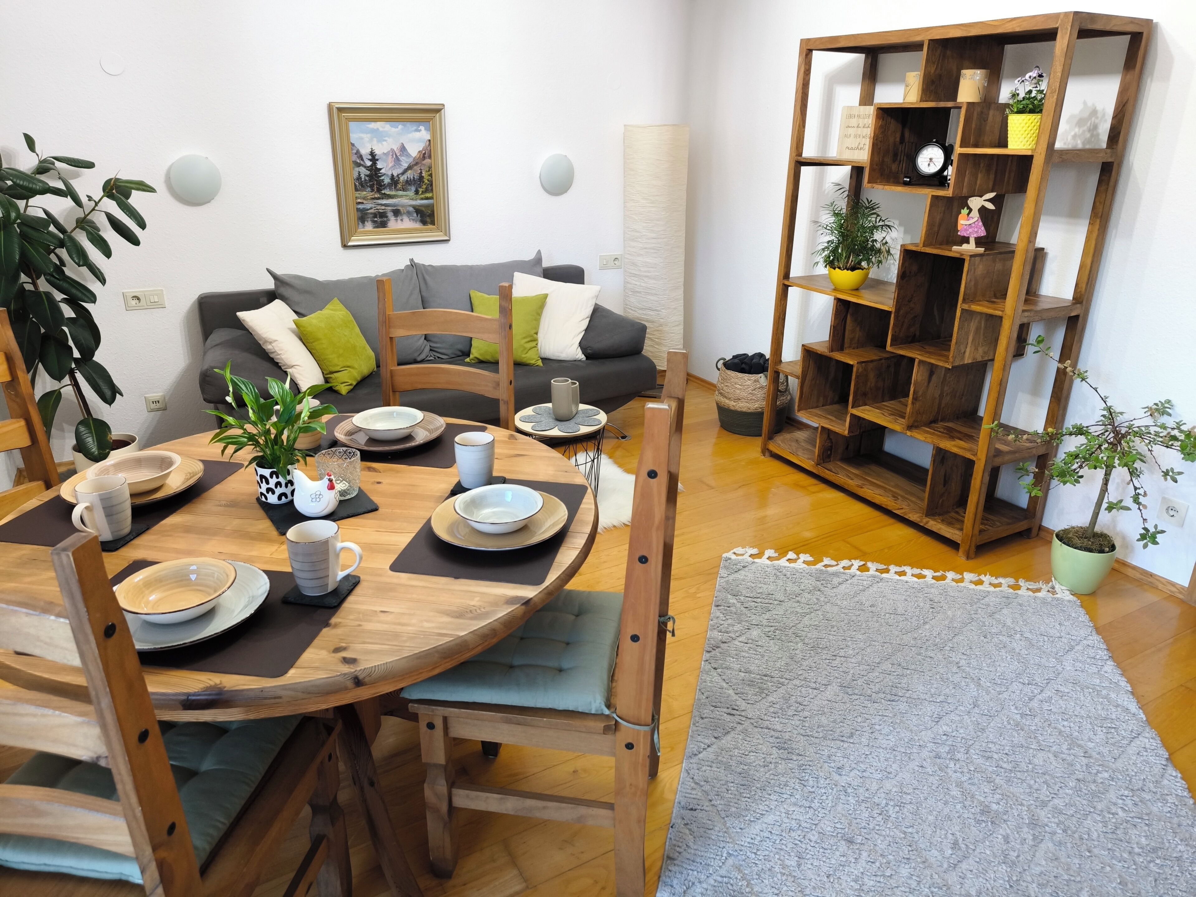 Ein Essbereich mit einem runden Holztisch, Stühlen und einem Bücherregal im Hintergrund.