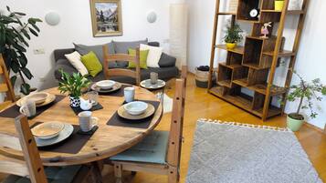 Ein Essbereich mit einem runden Holztisch, Stühlen und einem Bücherregal im Hintergrund.