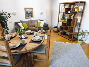 Un coin repas avec une table ronde en bois, des chaises et une bibliothèque en arrière-plan.
