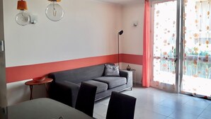 Een moderne woonkamer met een grijze bank, een eettafel met stoelen en hanglampen.