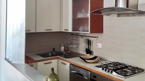 Een moderne keuken met witte kasten, een roestvrijstalen afzuigkap, een gasfornuis en een vaatwasser.