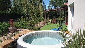 A backyard with a hot tub, wooden deck, and a patio area with a pergola. - House surrounded by nature and relaxation for the whole family (Faveraye-Machelles)