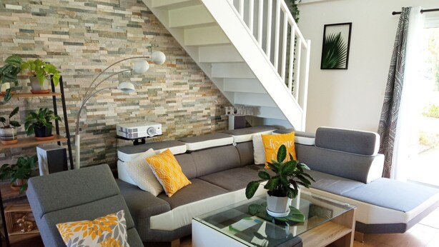 A modern living room with a sofa set, a coffee table, and a staircase. - House surrounded by nature and relaxation for the whole family (Faveraye-Machelles)
