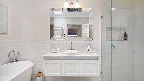 A modern bathroom with a freestanding bathtub, a sink with a mirror above, and a glass shower enclosure.