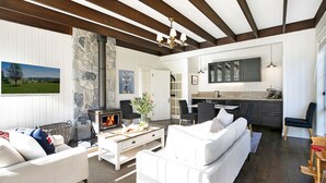 A modern living room with a fireplace, white furniture, and a stone accent wall. - Windermere – stunning and garden setting (Burradoo)