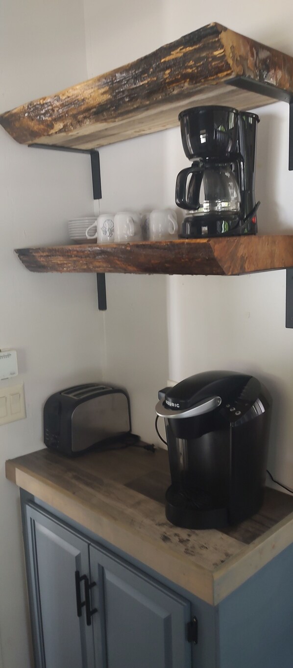 A kitchen with a wooden countertop, a coffee maker, a toaster, and a shelf with mugs and plates. - Gorgeous lake view (Hadley)