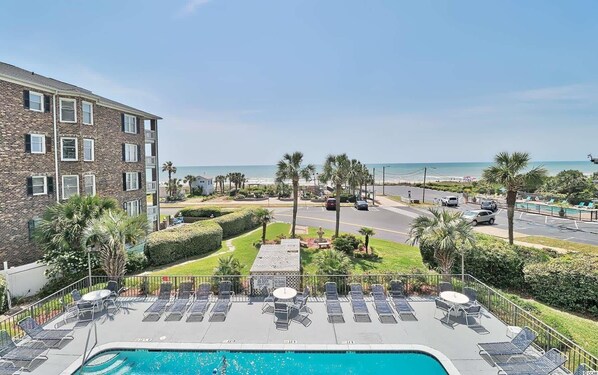 A pool area with lounge chairs and a view of the beach. - Cabana One Unit 302 (Myrtle Beach)