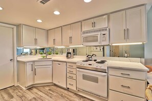 A modern kitchen with white cabinetry, a built-in microwave, a stove, and a dishwasher. - Cabana One Unit 302 (Myrtle Beach)