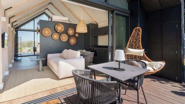 An open-plan living area with a sofa, dining table, and chairs, a hanging chair, and a kitchen area. - FONTE SANTA Manor House (Vila Nova de Gaia)