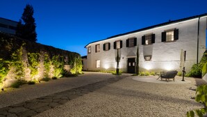 A building with a gravel driveway, a bench, and a well-lit entrance. - FONTE SANTA Manor House (Vila Nova de Gaia)