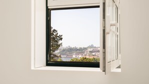 A window with a view of a cityscape, including buildings and a body of water. - FONTE SANTA Manor House (Vila Nova de Gaia)